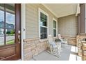 Inviting front porch with stone details, rocking chairs, and decorative pillows at 200 Baskerville Ct, Holly Springs, NC 27540
