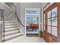 Light-filled foyer with staircase, marble floors, and a view into the dining room with blue walls and trim at 204 Franconia Way, Apex, NC 27502