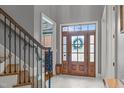 Bright foyer with wood door with glass inserts, white marble floors, and staircase with decorative iron railings at 204 Franconia Way, Apex, NC 27502