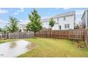 Spacious backyard featuring lush green grass, mature trees, and a wooden privacy fence at 212 Sea Trail St, Hillsborough, NC 27278