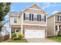 Inviting two-story home boasts stylish neutral siding, black shutters, and an attached two-car garage at 212 Sea Trail St, Hillsborough, NC 27278