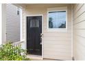 Close-up of front entrance with black door and window, complemented by neutral siding and lush greenery at 212 Sea Trail St, Hillsborough, NC 27278