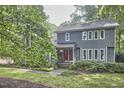 Two-story home with a red door and well-maintained front yard surrounded by mature trees and shrubbery at 2334 Dawn Trl, Durham, NC 27712