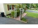 Landscaped yard featuring a decorative arbor with climbing vines, an asphalt driveway, and vibrant green grass at 2410 Wade Hampton Rd, Hillsborough, NC 27278