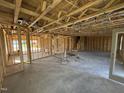 Unfinished living room showing stud walls, concrete floor, and staircase leading to the second floor at 29 Chloe Ct, Selma, NC 27576