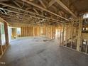Unfinished living room showing open layout with stud walls, concrete floor, and doorway leading to the backyard at 29 Chloe Ct, Selma, NC 27576