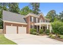 Spacious brick home with a three-car garage, a welcoming covered porch, and classic black shutters at 325 Wescott Ridge Dr, Holly Springs, NC 27540