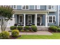 Inviting front porch with stone accents, comfy seating, decorative plants, and a stylish front door with house number displayed at 404 Wanderview Ln, Holly Springs, NC 27540