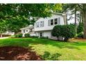 Charming two-story home with white painted brick, gray shutters, mature trees, and a beautifully landscaped front yard at 433 Rosehaven Dr, Raleigh, NC 27609