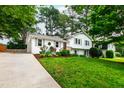 Charming two-story home with white painted brick, gray shutters, mature trees, long driveway, and a lush front yard at 433 Rosehaven Dr, Raleigh, NC 27609