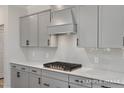 Close-up of a kitchen featuring white quartz countertops, gray cabinetry, and a stylish gas range at 4824 Bristol Meadow Dr, Raleigh, NC 27603