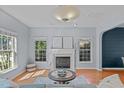 Cozy living room with a fireplace, large windows, and hardwood floors at 6004 Solitude Way, Durham, NC 27713