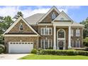 Grand brick home with a manicured lawn, white trim, two-car garage, and arched window details at 825 Highwater Pl, Fuquay Varina, NC 27526