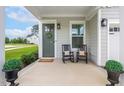 Inviting front porch with rocking chairs, a welcome wreath, and lovely potted plants at 100 Emory Bluffs Dr, Holly Springs, NC 27540