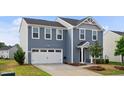 Inviting two-story home with a two-car garage, classic blue siding, and lush landscaping at 1004 Summer Mist Ln, Durham, NC 27704