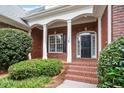 Inviting brick porch with white columns and black door, surrounded by manicured landscaping at 122 Barringer Dr, Garner, NC 27529