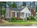 Side view of charming Cape Cod-style home featuring a brick and siding facade, complemented by lush greenery at 213 Bracken Ct, Raleigh, NC 27615
