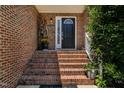 Inviting front porch with brick stairs, decorative plants, and a classic black front door at 2302 Fordcrest Dr, Apex, NC 27502