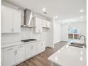 Modern kitchen boasts white cabinets, stainless steel range hood, and an open layout connecting to the living area at 2613 Red Spruce Dr, Raleigh, NC 27616