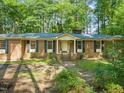 Inviting brick home featuring a classic front porch with columns and dark shutters against the windows at 3006 Pump Station Ln, Durham, NC 27712