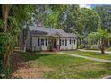 Charming home with mature trees, green lawn, dark shutters, and attractive landscaping at 308 Greenwood Dr, Durham, NC 27704