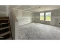 Unfinished living room featuring large windows, a staircase, and ready for personalization at 37 Chloe Ct, Selma, NC 27576