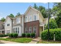 Townhome with brick facade and manicured lawn in a residential neighborhood surrounded by mature trees at 4413 Sugarbend Way, Raleigh, NC 27606