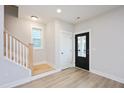 Bright entryway featuring light wood floors, stairs, and modern black door at 524 Folk Song Way, Wendell, NC 27591