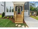 Inviting covered front porch featuring natural wood stairs, a red front door, and manicured landscaping at 905 Deboy St, Raleigh, NC 27606