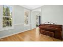 Bright, empty room with hardwood floors, large windows, and piano at 1003 Blackberry Ln, Durham, NC 27712