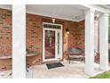 Covered porch features brick columns, bench seating, and a charming front door with glass panels at 10310 Sablewood Dr # 115, Raleigh, NC 27617