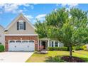 Beautiful two-story home boasts a two-car garage, brick accents, manicured lawn, and a mature shade tree at 1108 Forest Willow Ln, Morrisville, NC 27560