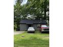 Cozy gray home with a dark roof, surrounded by lush greenery and parked cars at 12600 Old Stage Rd, Willow Springs, NC 27592