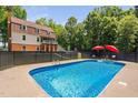 Large in-ground swimming pool with an iron fence and red umbrellas, ideal for outdoor relaxation at 1909 Ira Rd, Efland, NC 27243