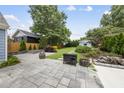 Spacious backyard featuring a stone patio, fire pit, mature trees, and a charming storage shed at 208 Maywood Ave, Raleigh, NC 27603