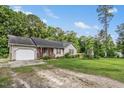 Traditional single-story home with a garage, covered porch, and a well-manicured lawn under a bright blue sky at 229 White Oak Farm Dr, Willow Springs, NC 27592