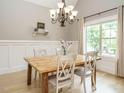 Bright dining room with wainscoting, a wooden table, and a modern chandelier at 3021 Lawson Walk Way, Rolesville, NC 27571