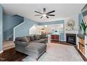 Cozy living room with blue walls, a ceiling fan, a fireplace, and a comfortable gray sectional couch at 5505 Heather Garden Way, Raleigh, NC 27613