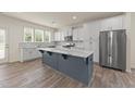 A modern kitchen with white cabinets, stainless steel appliances, and a large center island with a marble countertop at 908 Adelphia Rd, Fuquay Varina, NC 27526