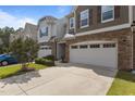 An exterior view of three townhomes showcasing their stone accents, driveways, and manicured landscaping at 9302 Nellman Ln, Raleigh, NC 27617