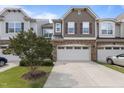 An exterior view of townhomes featuring stone accents, a driveway, and well maintained landscaping at 9302 Nellman Ln, Raleigh, NC 27617