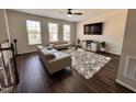 Well-lit living room showcasing hardwood floors, stylish sofas, a modern rug, and a sleek ceiling fan at 1005 Lathrop Ln, Apex, NC 27523