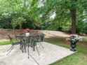 Outdoor patio with a table, chairs, and elegant flower pots, surrounded by lush greenery and mature trees at 101 Lake Tillery Dr, Cary, NC 27519