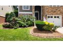 Close-up of the front yard featuring lush landscaping, colorful flowers, and a well-manicured lawn at 1016 Dotson Way, Apex, NC 27523