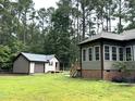 Sprawling backyard with a view of the accessory building and the home's window-enclosed sunroom at 105 Perry Ln, Zebulon, NC 27597