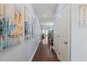 Long hallway with wood floors and light blue walls showcasing stylish decor and access to various rooms at 108 Hundred Oaks Ln, Holly Springs, NC 27540