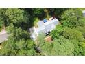 Aerial view of a home surrounded by mature trees, featuring a patio with outdoor seating and a blue umbrella at 12037 Deer Run, Raleigh, NC 27614