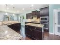 Spacious kitchen featuring dark wood cabinets, granite countertops, stainless steel appliances, and a central island at 1305 Ivey Grove Ct, Fuquay Varina, NC 27526
