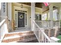 Inviting front porch with brick steps, white railings, a floral wreath on the black door, and a partially visible American flag at 2027 Hopeton Ave, Raleigh, NC 27614