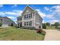 Side view of an elegant home with attached garage, paved driveway and landscaped yard at 243 E Wellesley Dr, Clayton, NC 27520